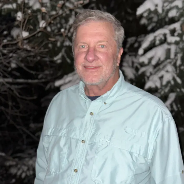 A man standing in front of snow covered trees.