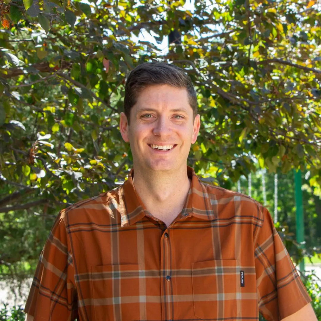 A man in an orange shirt smiling for the camera.